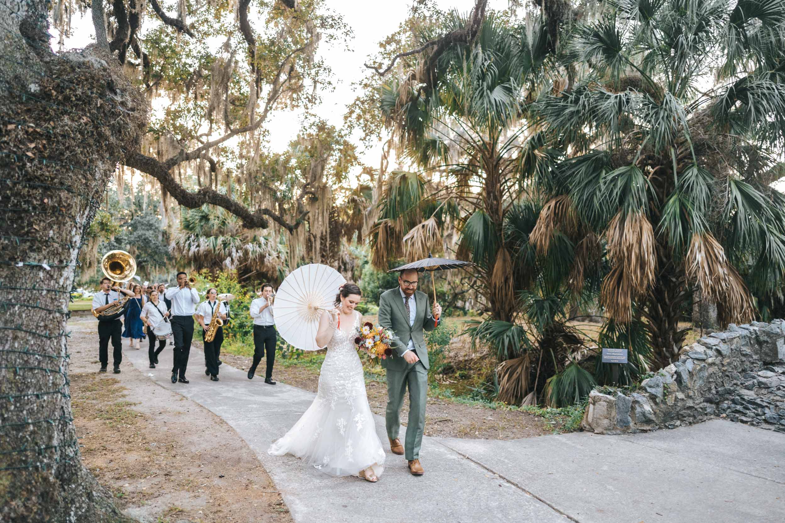 bride and groom celebrating with a 2nd line band on wedding day in City Park of New Orleans