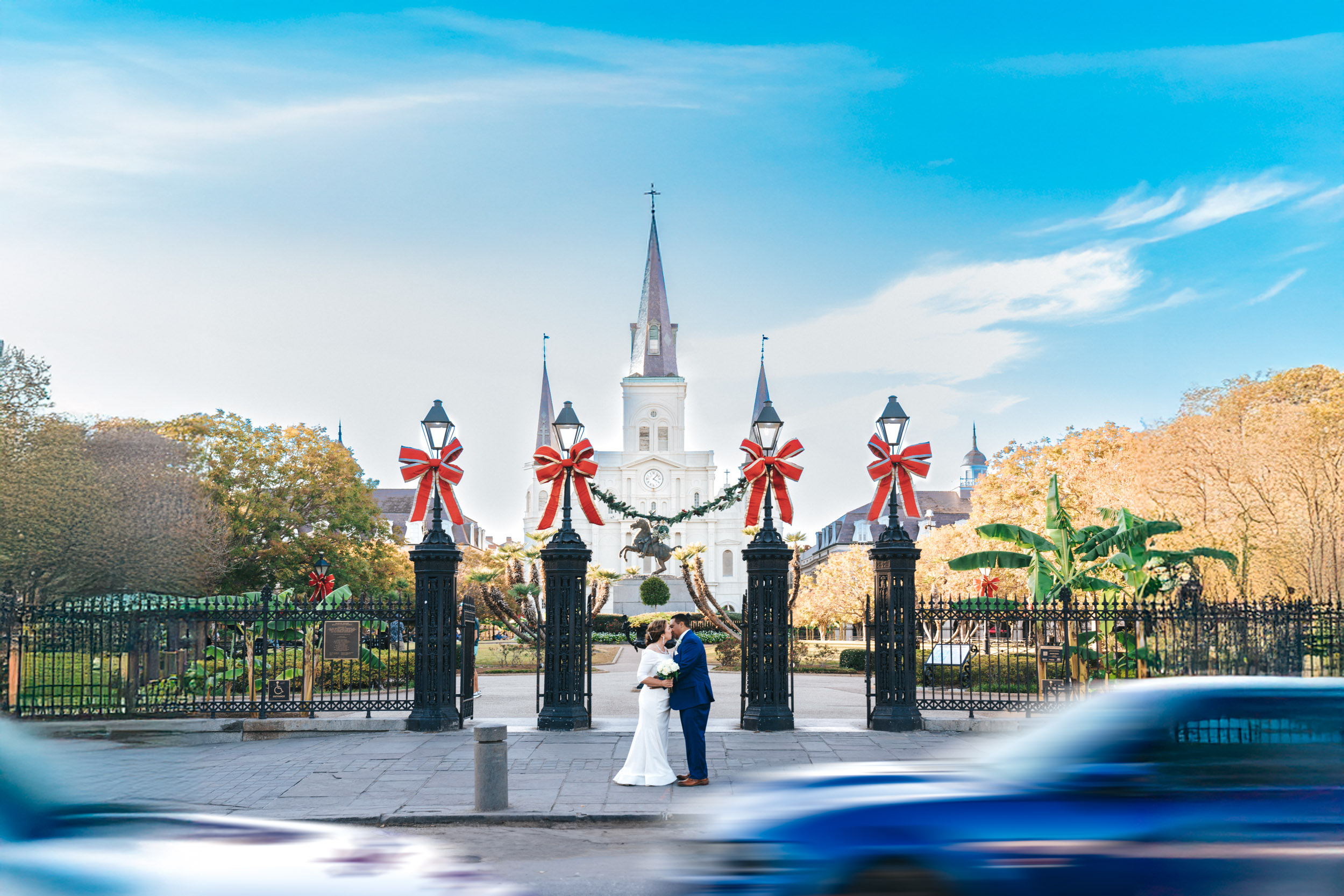 bride and groom kissing in front of Jackson Square with cars passing by in New Orleans