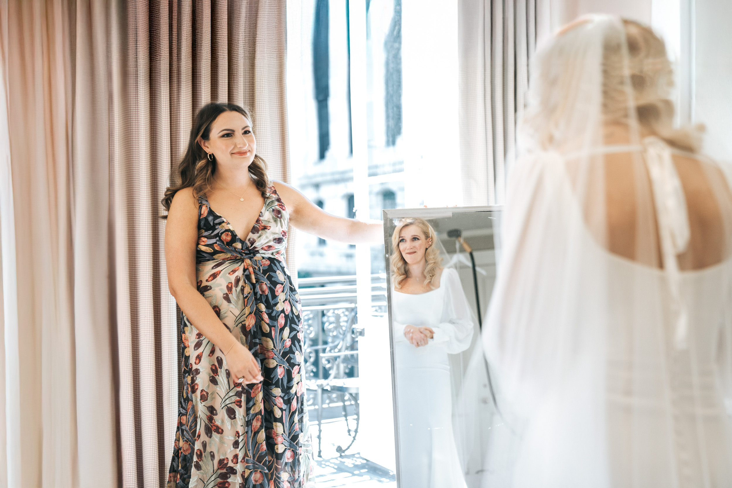 bride looking at bridesmaid through mirror on French Quarter balcony at the Bourbon Orleans in New Orleans