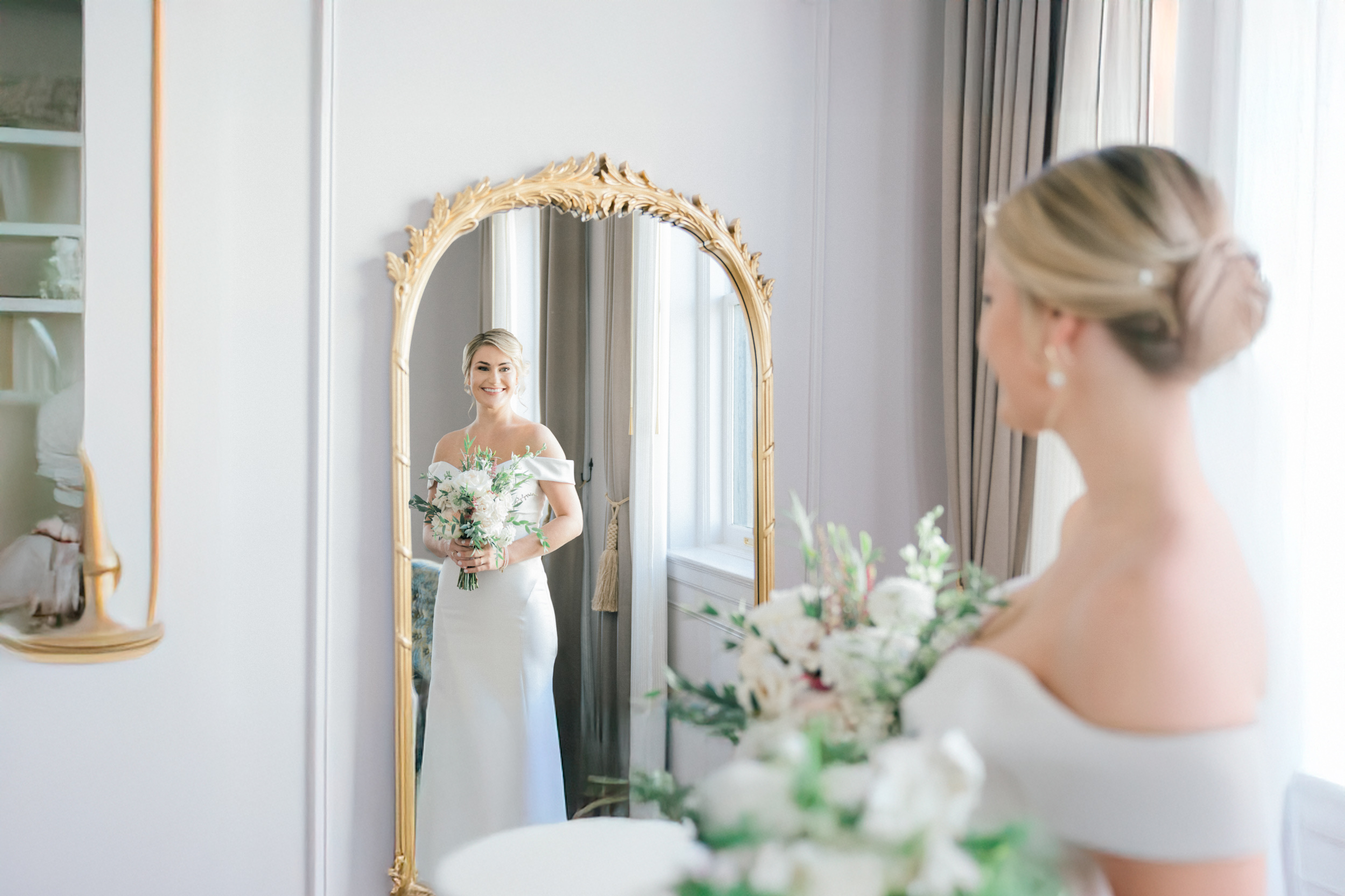 bride looking in mirror with flowers on wedding day at the Maison De La Luz Hotel in New Orleans