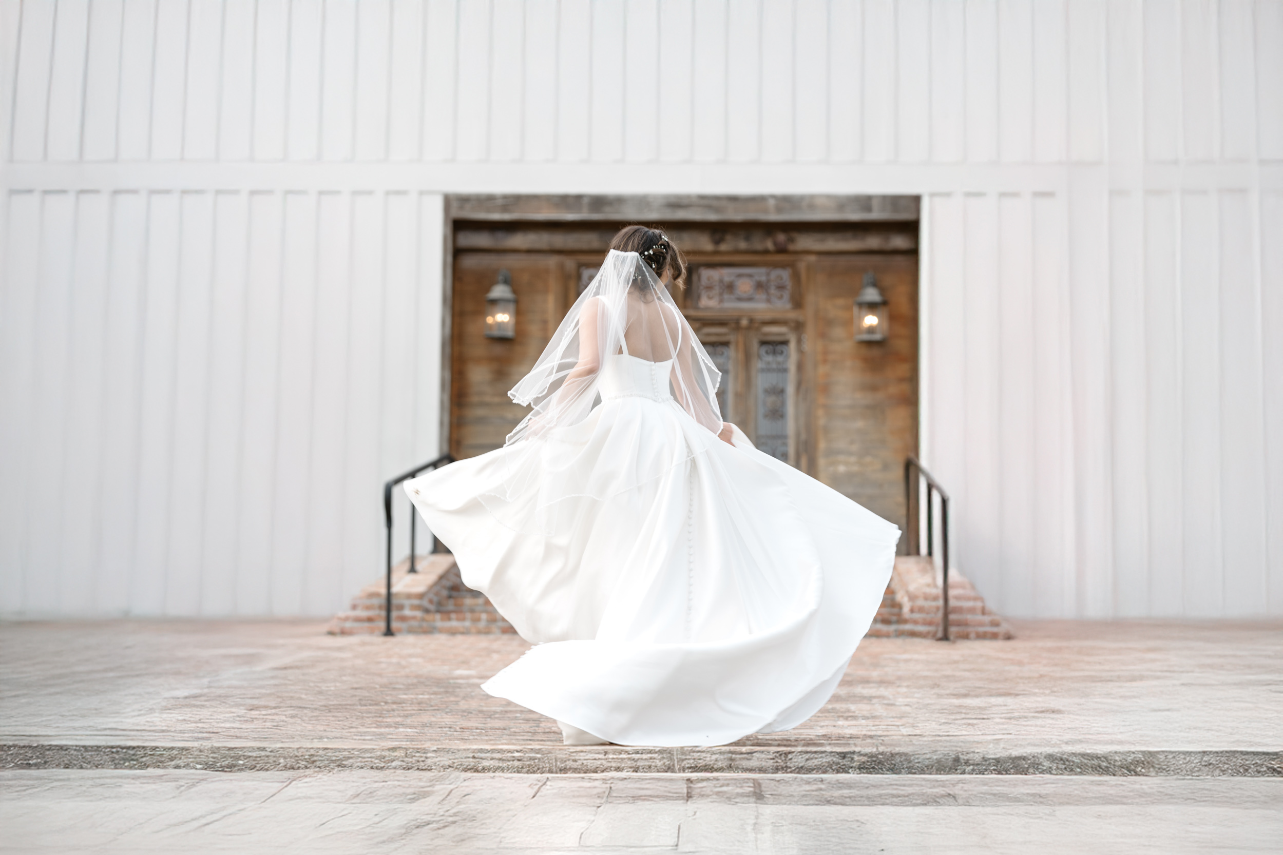 bride waving her wedding dress around in the air in front of church at White Magnolia in Kentwood, LA